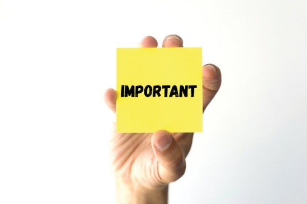 Hand holding yellow sticky note that says important