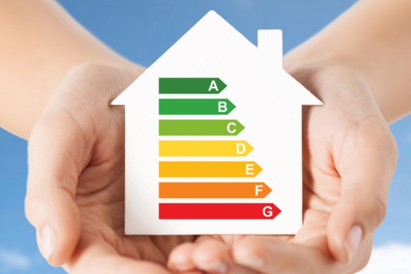 Hands holding cutout paper house with efficiency meter image inside
