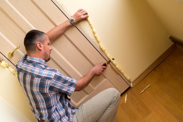 homeowner sealing air leaks beside the door