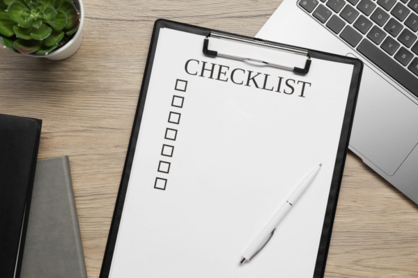Clipboard with checklist, pen and laptop on wooden table depicting Choose the Right Air Conditioner Replacement Contractor