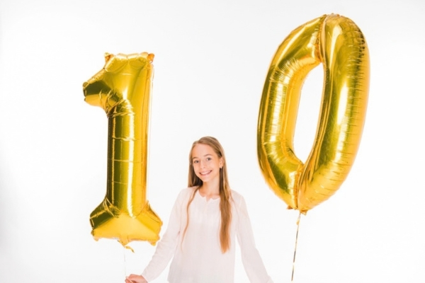 young lady holding number 10 golden balloon depicting Effective Ways to Lower Heating Oil Costs