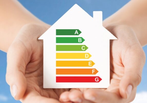 Hands holding cutout paper house with efficiency meter image inside